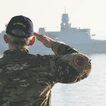 Forsiden af forsvarsforliget 2024-2033. Soldat gør honnør til fregat